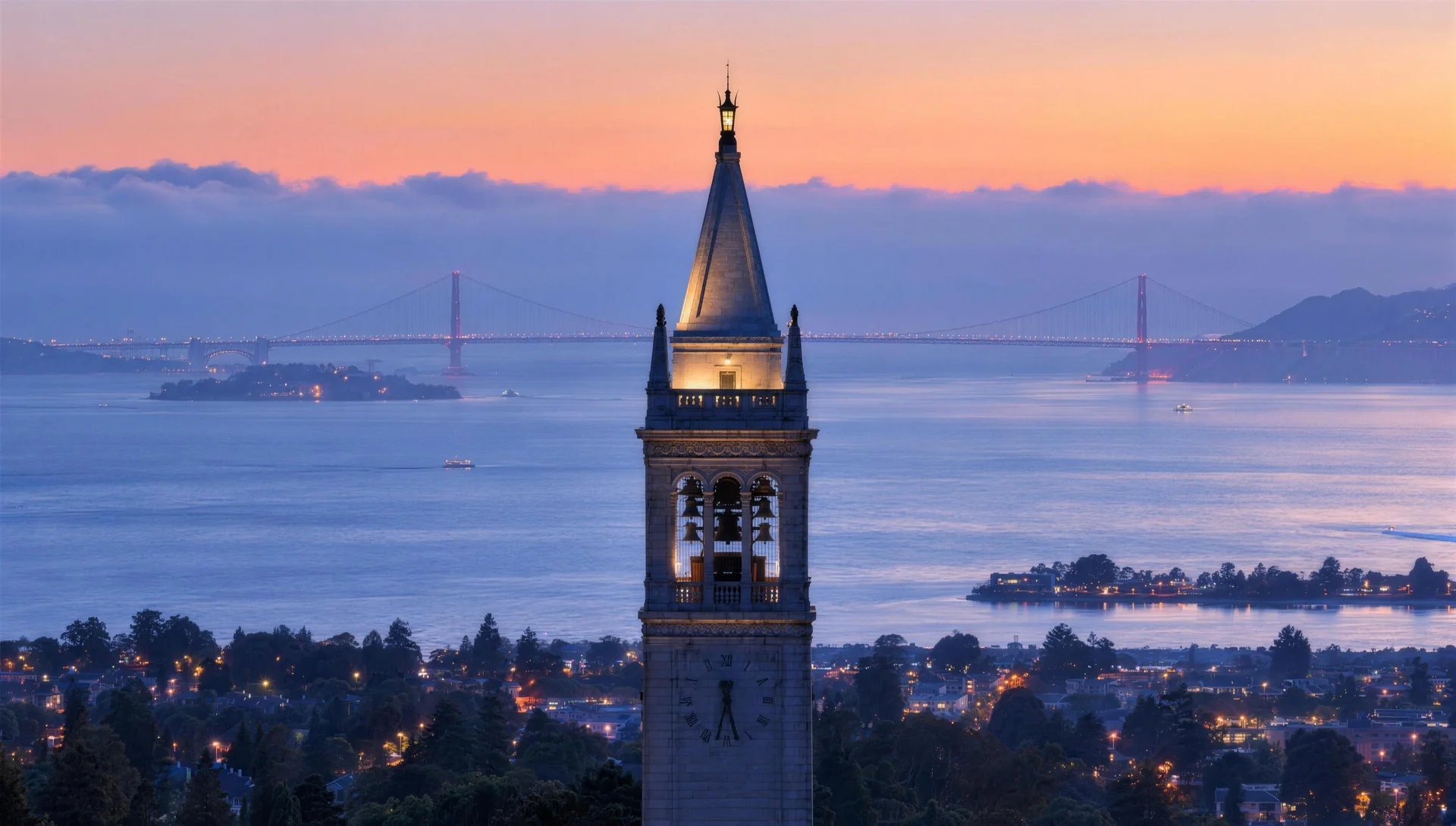 The Campanile at dusk, its belfry lit, with the Golden Gate Bridge beyond.